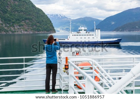 Tourism vacation and travel. Tourist woman on cruise ship enjoying fjord view, taking photo with camera. Norway Scandinavia Europe. Norddalsfjorden as seen from ferry.