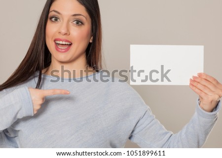 Smiling woman showing empty blank paper card sign with copy space for text
