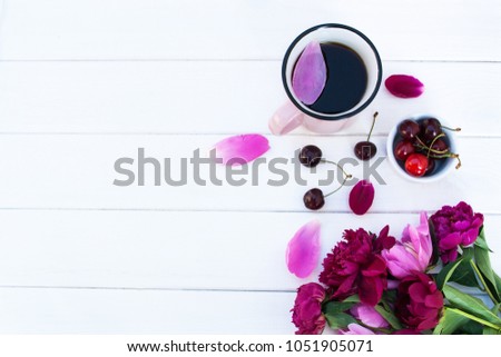 Coffee in a mug, peonies and cherry on a white wooden background