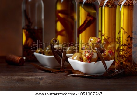 Spiced green olives and bottles with olive oil on a wooden table. 