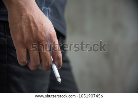 Close up male hand holding a cigarette. Royalty-Free Stock Photo #1051907456