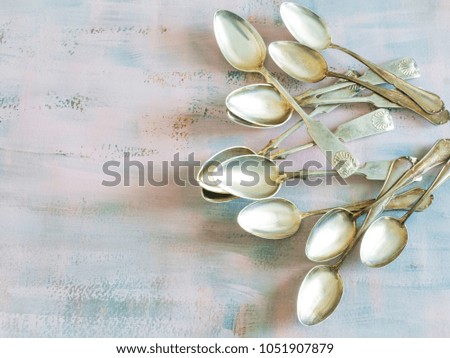 Vintage silver spoons on a painted pastel colored background