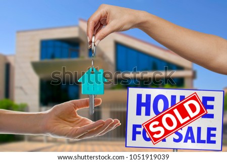 Handing Over the House Key in Front of Sold New Home Against a Blue Sky. Real Estate Business Concept