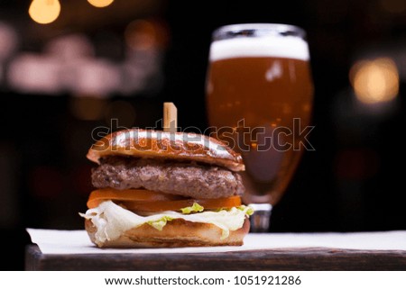 Tasty grilled prawn and beef burger with lettuce and mayonnaise served on pieces of white paper on a rustic wooden table of counter, with copyspace