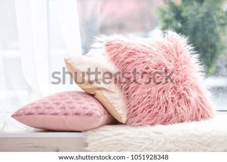 Different soft pillows on windowsill