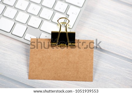 Business card in brown color with golden clamp on computer keyboard. Mockup.