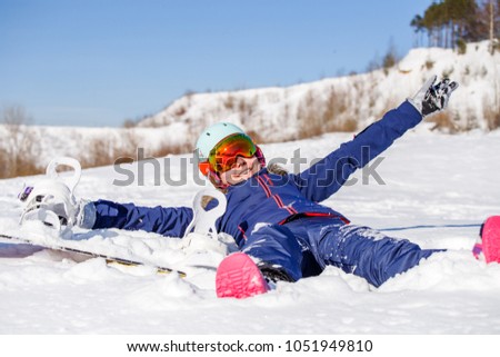 Phptp of happy athlete woman in helmet lying in snowdrift