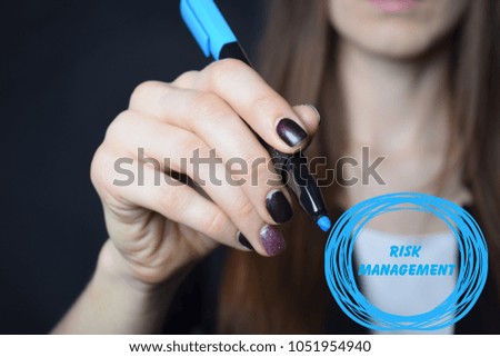 The businessman writes a blue marker inscription:RISK MANAGEMENT