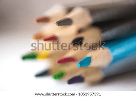 Pile of sharp coloured drawing pencils on table. Rainbow colors - red, yellow, blue, green, purple. Concept of art, crafts and kids having fun