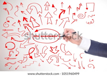 The businessman writes a red marker inscription:RISK MANAGEMENT
