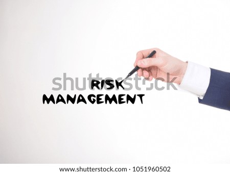 The businessman writes a black marker inscription:RISK MANAGEMENT