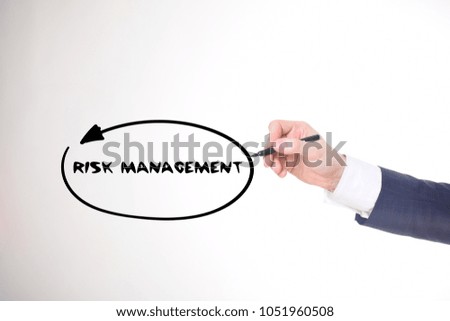 The businessman writes a black marker inscription:RISK MANAGEMENT