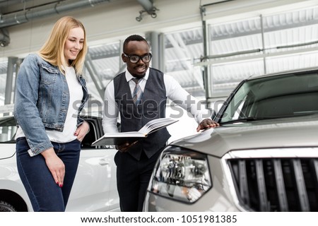 Sales consultant shows the girl a new car to buy Royalty-Free Stock Photo #1051981385