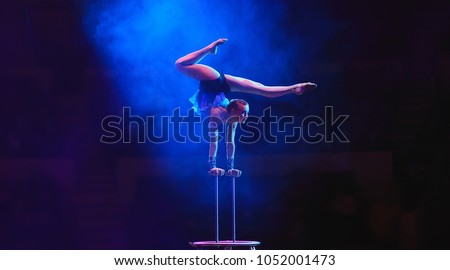 Aerial acrobat in the ring. A young girl performs the acrobatic elements in the air ring. Royalty-Free Stock Photo #1052001473