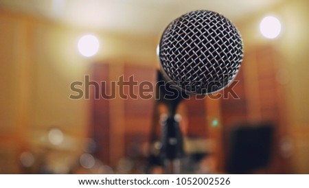 Music concept microphone on blurred background of live recording studio with bokeh defocused lights. (close up, selective focus, space for text)