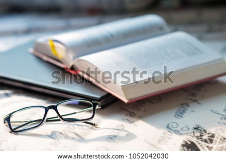 Literature knowledge concept of book laptop and eye glasses on cozy bed in room
