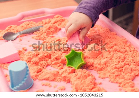 The hands of a child playing with kinetic sand.