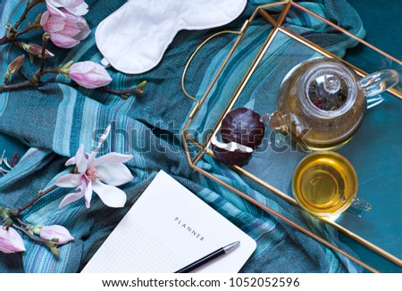 Breakfast in bed flat lay with magnolia flowers and green tea with marshmallows. Tea break concept. Top view spring composition
