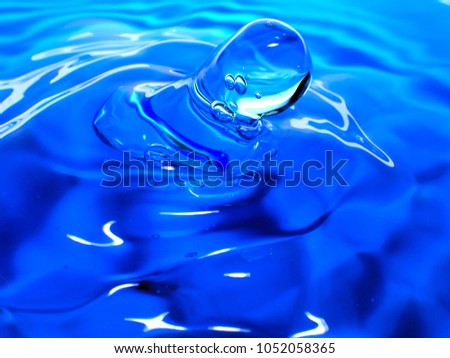 Macro photography of blue water drop / ink drops splash and ripples, wet, conceptual for environmental, conservation, drought, artistic, for website banners, backgrounds, and graphics with copy space.
