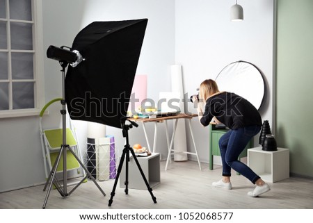 Woman taking photo of food with professional camera in studio