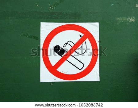 The sign-smoking is forbidden, pasted on the old wall painted in green.