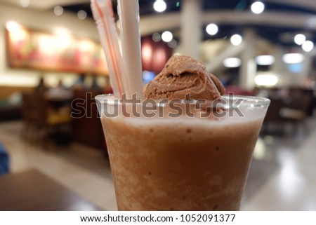 Ice Cream Chocolate combine with milk - very fresh and cold. Brown cream with some bubble compose the delicious ice cream in the glass. Composition of ice cream, glass and the straw combine good pictu