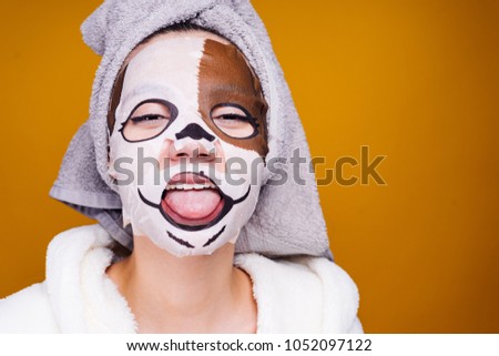 funny young girl with a towel on her head showing tongue, on face mask with dog face
