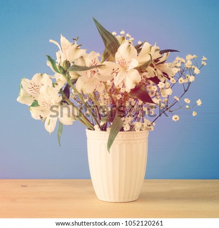 summer bouquet of white flowers in the vase over wooden table and blue background