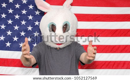 A man wears a Easter Bunny or White Rabbit mask while posing in front of an American Flag in a Photo Booth. Photo Booths are popular at Weddings and all Parties. Everyone loves a good photo booth.