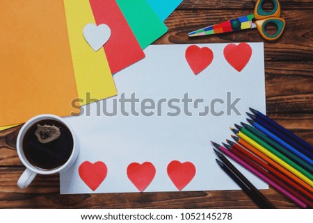 wooden background with colored pencils, colored paper and coffee