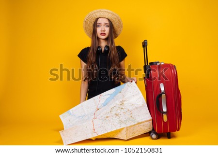beautiful young long-haired girl in a hat went on a trip with a suitcase and a card