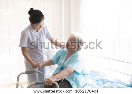 Nurse with patient. Routine health check and assisting elderly patient to walk. Female nurse with senior chinese woman. Royalty-Free Stock Photo #1052178401