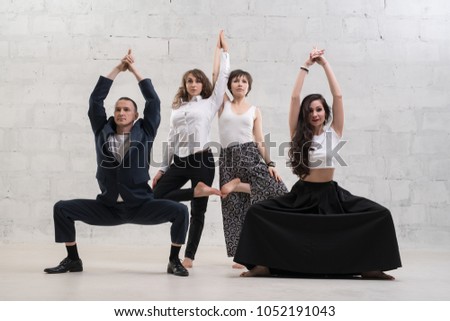 People in office clothes doing yoga against wall