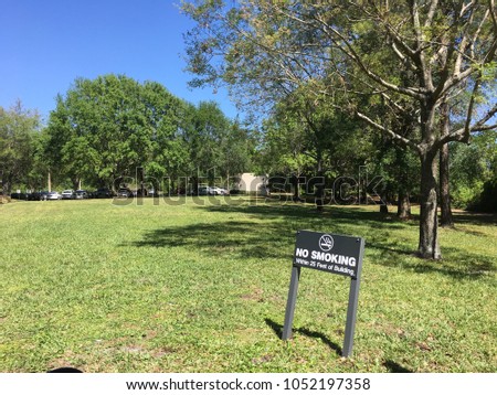 Garden with trees, blue sky and "no Smoking" sign