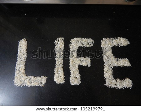 "LIFE" text written on black stone with rice grains