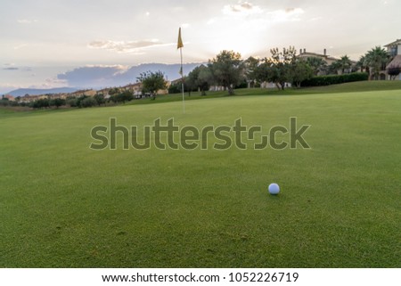 Golf ball on green fairway blue cloudy summer sky in the background