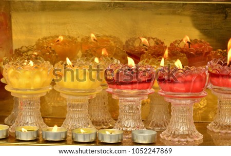 The worship candle in a glass lotus container.