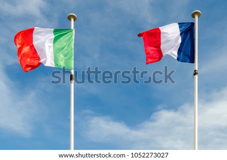 An italian and french flags are floating in a blue sky