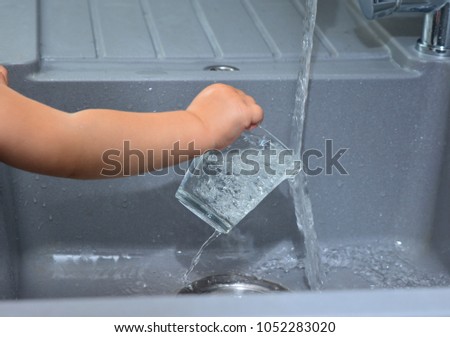 girl holding a glass in her hands and pouring water Faucet