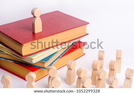 A man stands on a pile of books before the audience and makes a speech. A smart leader manages employees and leads them along. Concept of agitation, strike, announcement. Briefing before work