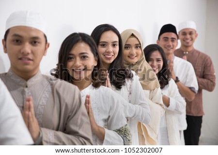 Group of muslim asian men and women smiling and greeting. embracing each other during eid mubarak celebration