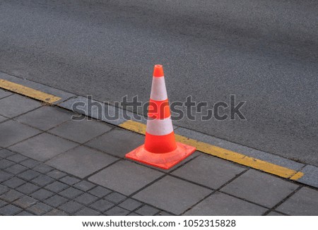 Traffic cone with red and white parts on asphalt
