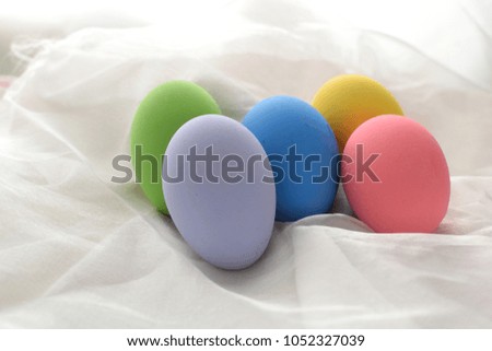 Multi-colored eggs on white cloth.

