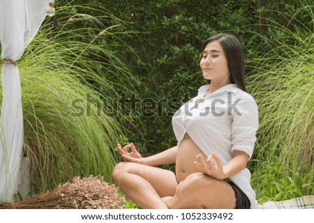 Concept of pregnancy.  Pregnant women are exercising. Pregnant women are taking care of their health with yoga. Pregnant woman playing yoga in the garden