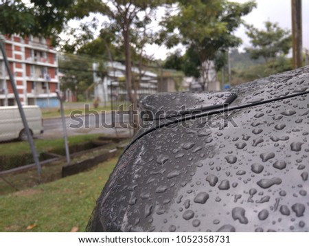Car details. Close up of grey car spoiler with raindrops.