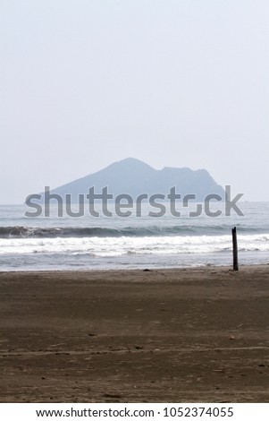 Guishan Island and Wai'ao beach, the waves and a driftwood erected on the beach in Yilan, Taiwan.