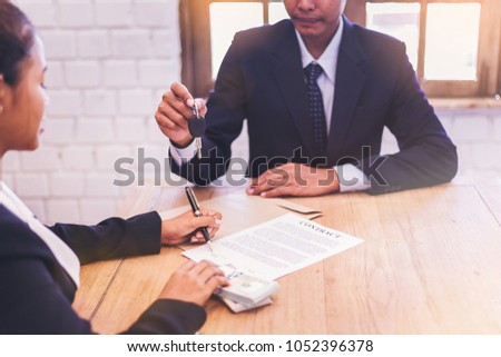 woman signing in contract for buy the car and seller giving the key for new car