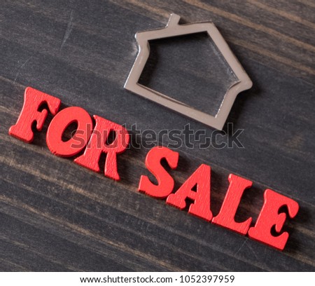 FOR SALE phrase with metal house symbol on wooden background