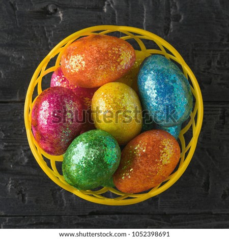 Basket with colorful eggs on a black table. The view from the top.