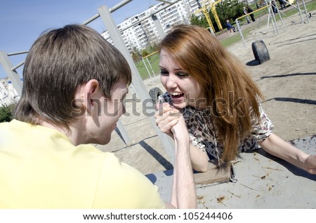 The couple, young man and woman in the heat of the fight - who in the family of the chief. Armwrestling - fight on their hands.